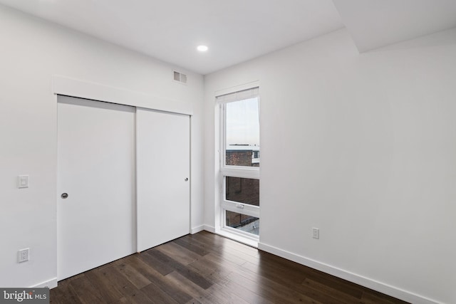 unfurnished bedroom with dark wood-type flooring and a closet