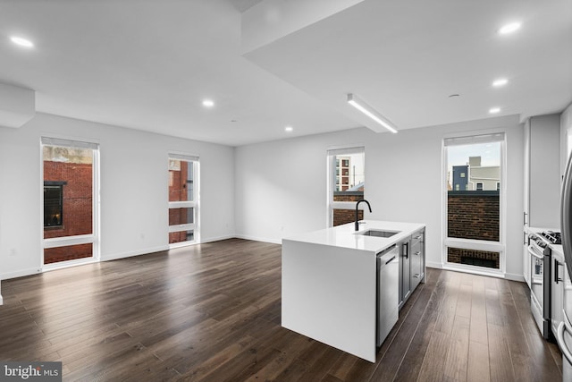 kitchen with stainless steel appliances, sink, a center island with sink, and dark wood-type flooring