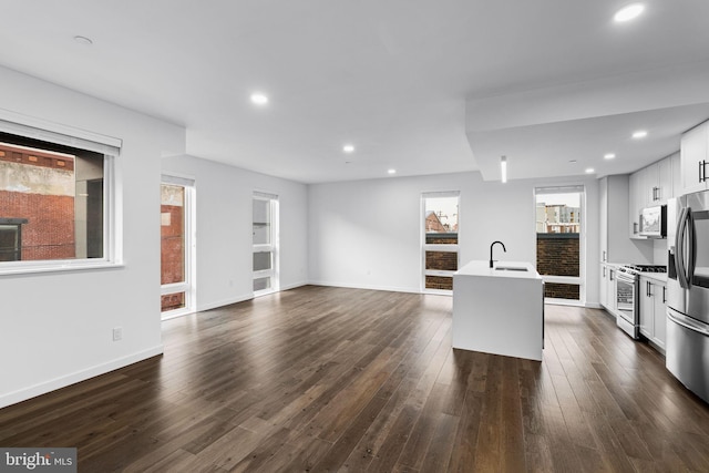 kitchen featuring sink, white cabinetry, stainless steel appliances, dark hardwood / wood-style floors, and an island with sink