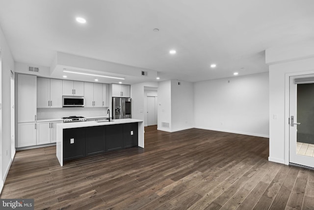 kitchen featuring sink, white cabinetry, a center island with sink, appliances with stainless steel finishes, and dark hardwood / wood-style flooring