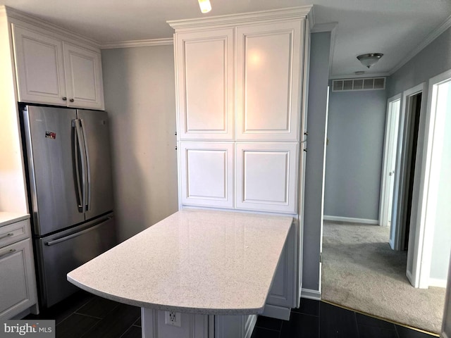 kitchen with stainless steel refrigerator, white cabinetry, ornamental molding, and dark colored carpet