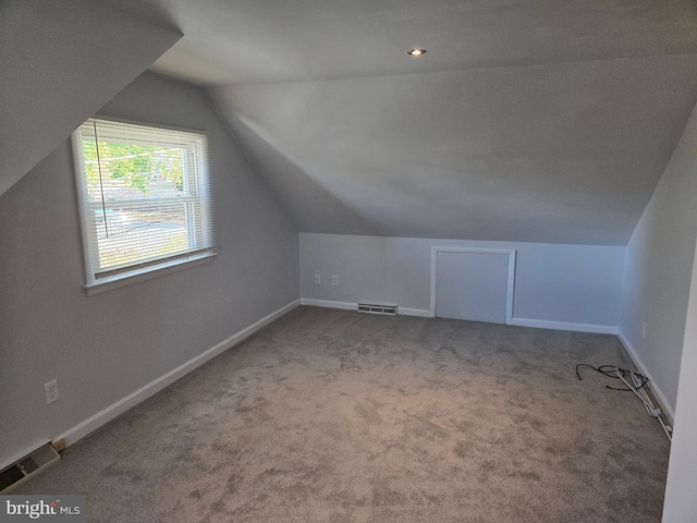 additional living space featuring lofted ceiling and light carpet