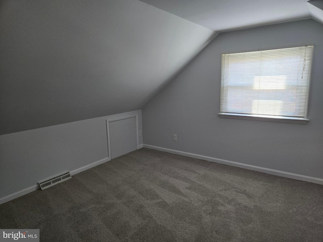 bonus room with vaulted ceiling and dark carpet