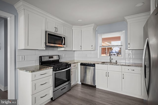 kitchen with sink, appliances with stainless steel finishes, dark hardwood / wood-style floors, white cabinets, and stone countertops