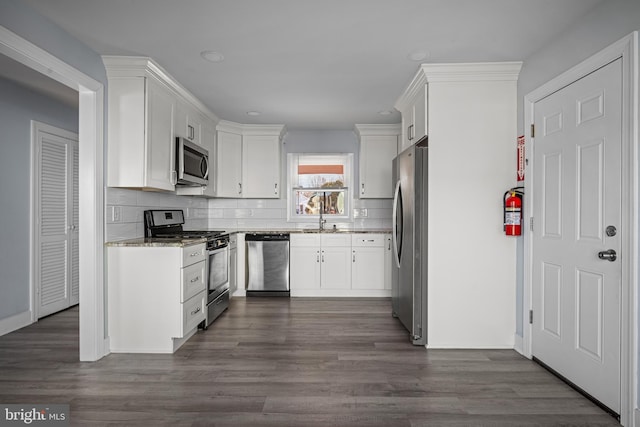 kitchen with tasteful backsplash, appliances with stainless steel finishes, dark hardwood / wood-style floors, and white cabinets