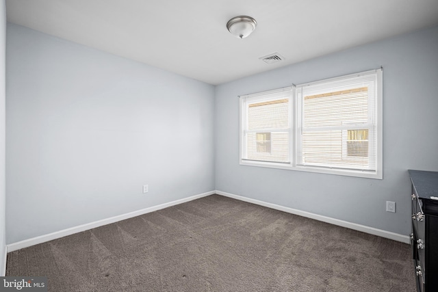 spare room with dark carpet