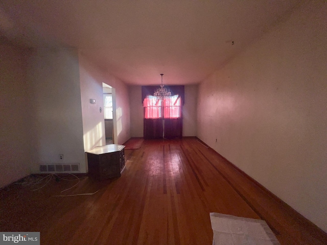 spare room featuring an inviting chandelier and hardwood / wood-style flooring