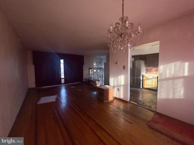 unfurnished living room featuring dark hardwood / wood-style floors and an inviting chandelier