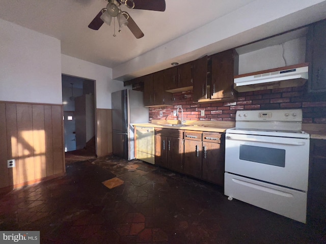 kitchen featuring ceiling fan, sink, wooden walls, and white appliances