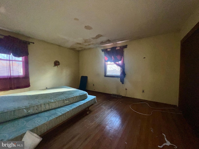 unfurnished bedroom with multiple windows and hardwood / wood-style flooring