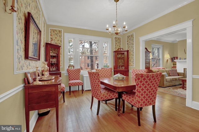 dining area featuring ornamental molding, light hardwood / wood-style flooring, and a notable chandelier