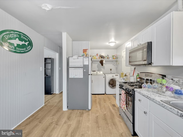 kitchen featuring independent washer and dryer, stainless steel appliances, light hardwood / wood-style floors, and white cabinets