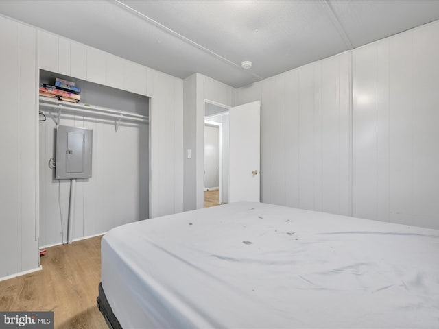 bedroom with a closet, electric panel, and light hardwood / wood-style floors