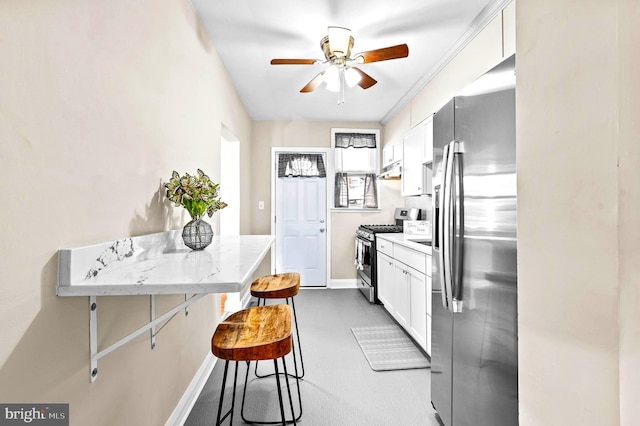 kitchen featuring ceiling fan, appliances with stainless steel finishes, white cabinetry, light stone countertops, and a kitchen bar