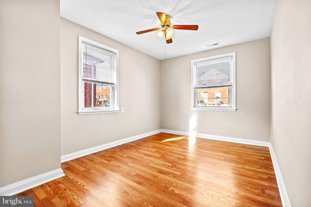 empty room with ceiling fan, a healthy amount of sunlight, and light hardwood / wood-style flooring