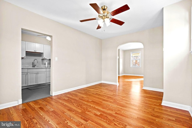 spare room featuring ceiling fan, sink, and light wood-type flooring