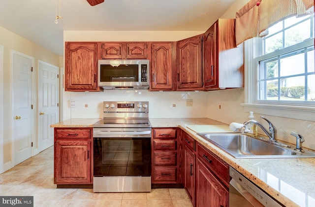 kitchen with light tile patterned flooring, appliances with stainless steel finishes, sink, and decorative backsplash