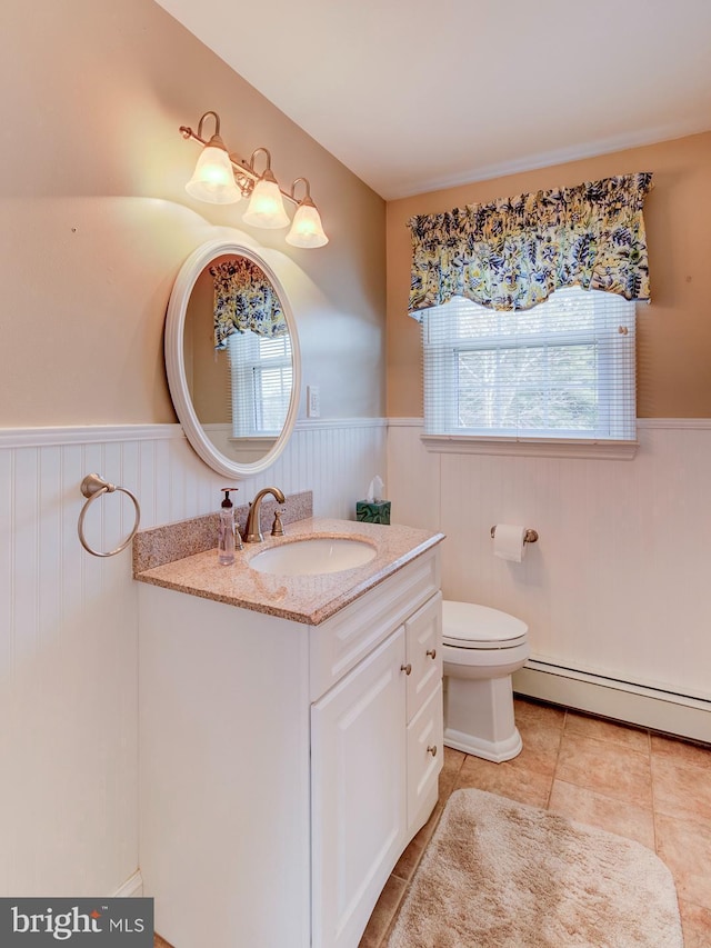 bathroom with vanity, plenty of natural light, baseboard heating, and toilet