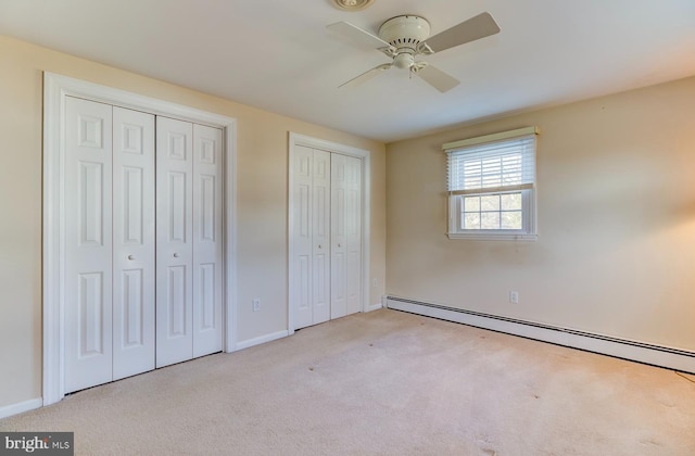 unfurnished bedroom with multiple closets, a baseboard radiator, light carpet, and ceiling fan