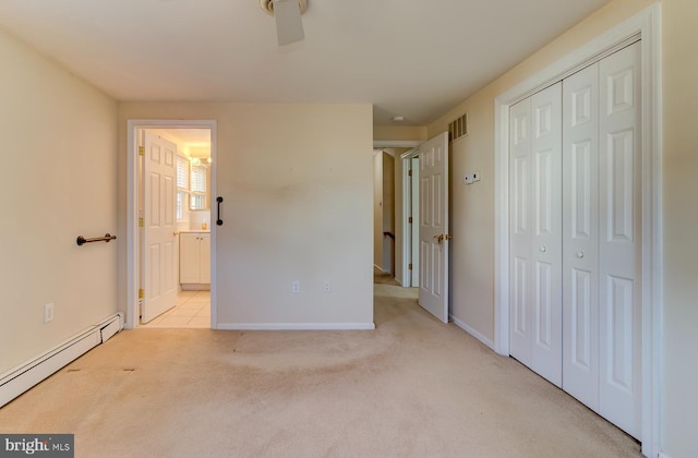 unfurnished bedroom featuring baseboard heating, a closet, ensuite bath, and light carpet