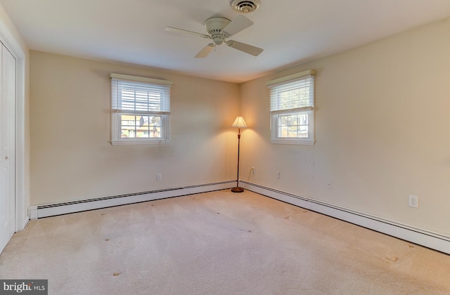 carpeted empty room featuring ceiling fan, a baseboard heating unit, and a wealth of natural light