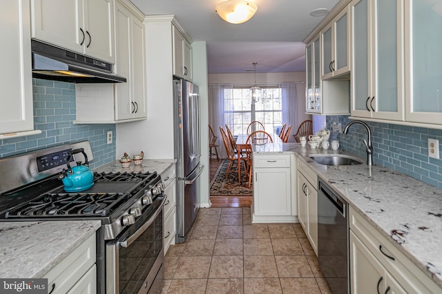 kitchen with pendant lighting, sink, stainless steel appliances, light stone counters, and light tile patterned flooring