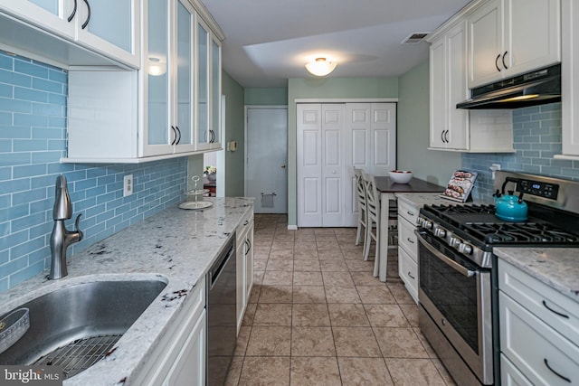 kitchen featuring sink, dishwasher, light stone countertops, white cabinets, and gas range