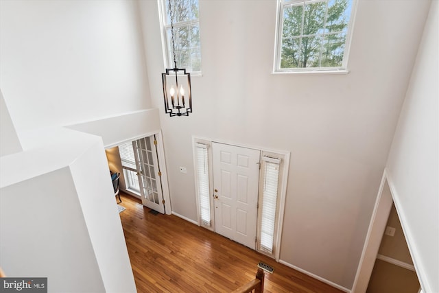 entryway with wood finished floors, visible vents, french doors, a towering ceiling, and a notable chandelier