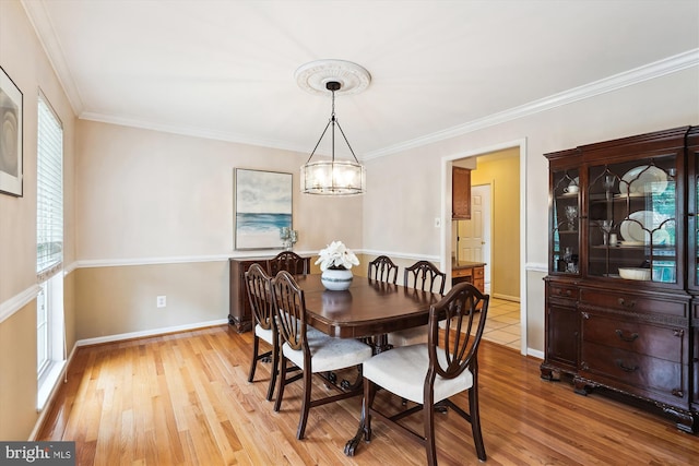 dining room with a chandelier, light wood finished floors, baseboards, and ornamental molding