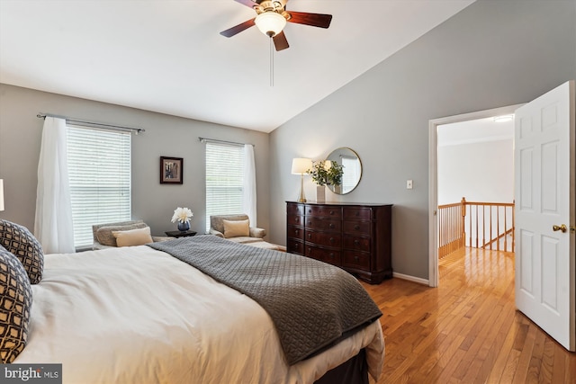 bedroom with ceiling fan, light wood-type flooring, baseboards, and vaulted ceiling