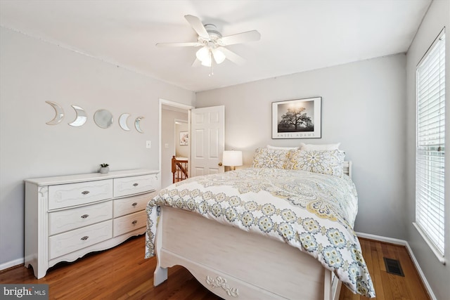 bedroom featuring visible vents, a ceiling fan, baseboards, and wood finished floors