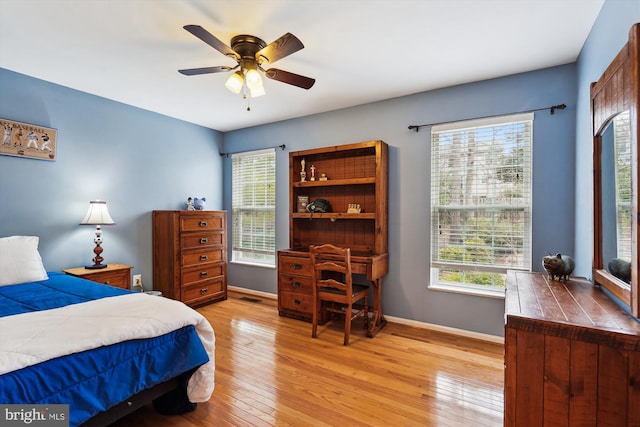 bedroom with multiple windows, baseboards, light wood-type flooring, and ceiling fan