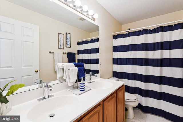 bathroom with a sink, toilet, double vanity, and tile patterned flooring