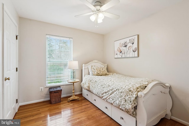 bedroom with light wood-type flooring, baseboards, and a ceiling fan