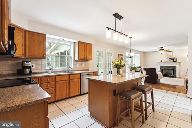 kitchen with light tile patterned flooring, a sink, brown cabinetry, and stainless steel dishwasher