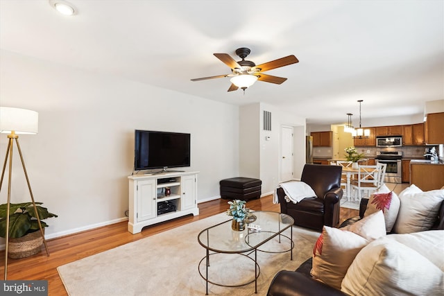 living area with baseboards, visible vents, a ceiling fan, and light wood-style floors