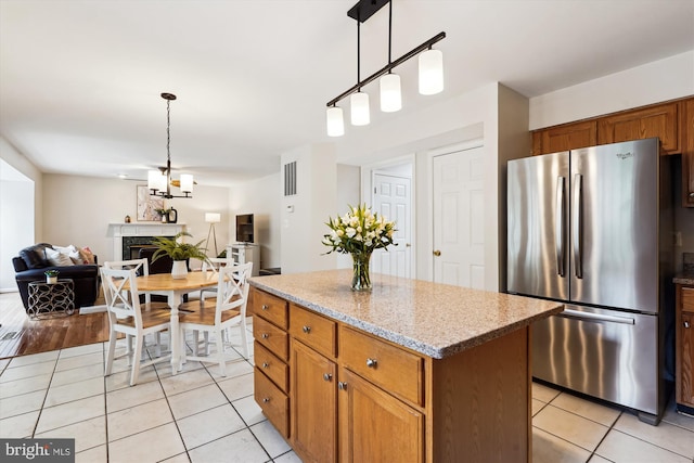 kitchen featuring light tile patterned floors, freestanding refrigerator, decorative light fixtures, open floor plan, and a center island