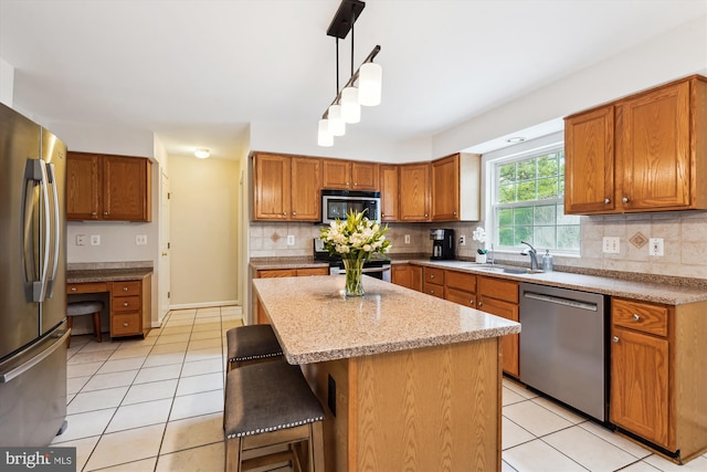 kitchen with a sink, a breakfast bar area, light tile patterned flooring, and stainless steel appliances