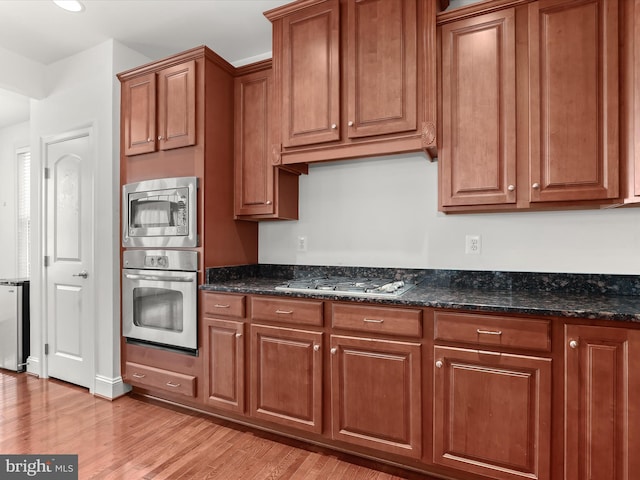 kitchen featuring stainless steel appliances, light hardwood / wood-style flooring, and dark stone countertops