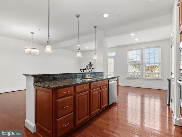 kitchen featuring hanging light fixtures, dishwasher, sink, and dark stone counters