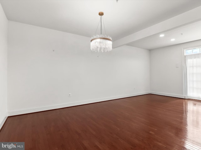 spare room featuring an inviting chandelier, dark hardwood / wood-style floors, and beamed ceiling