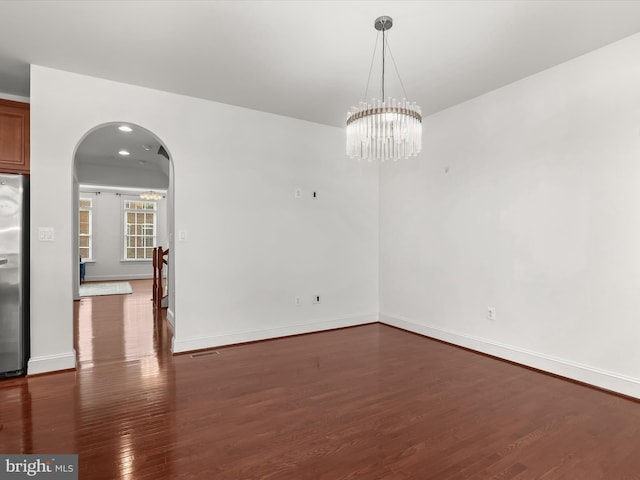 empty room featuring dark hardwood / wood-style flooring and a chandelier