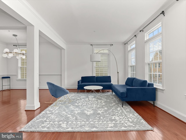 living area featuring crown molding, wood-type flooring, and a chandelier