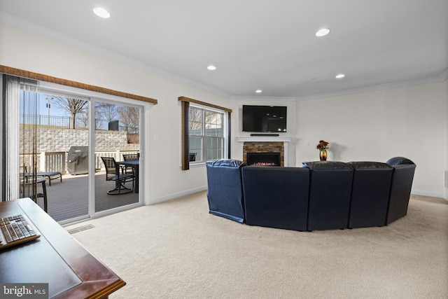 living area with ornamental molding, a stone fireplace, baseboards, and light colored carpet