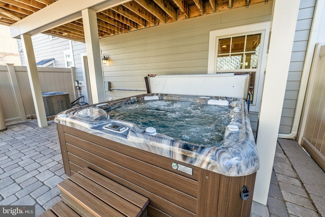 view of patio / terrace with central air condition unit, a hot tub, and fence