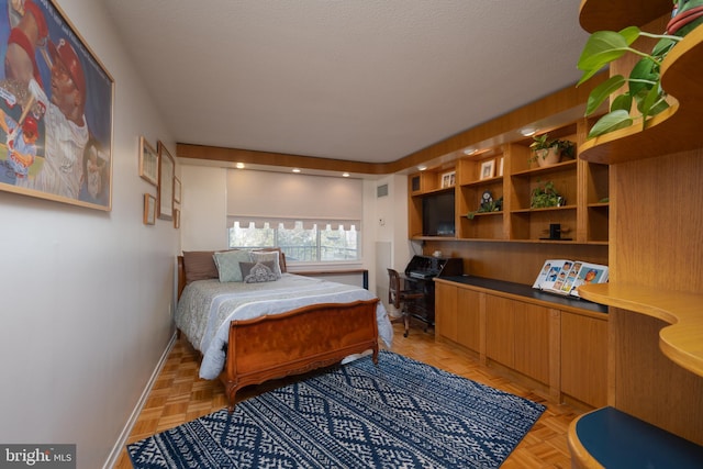 bedroom featuring light parquet flooring, built in desk, and a textured ceiling