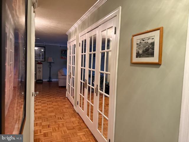 hall featuring french doors, ornamental molding, and light parquet flooring