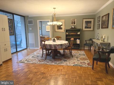 dining room with crown molding, light parquet flooring, and an inviting chandelier