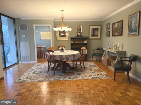 dining space featuring a notable chandelier, crown molding, and parquet floors