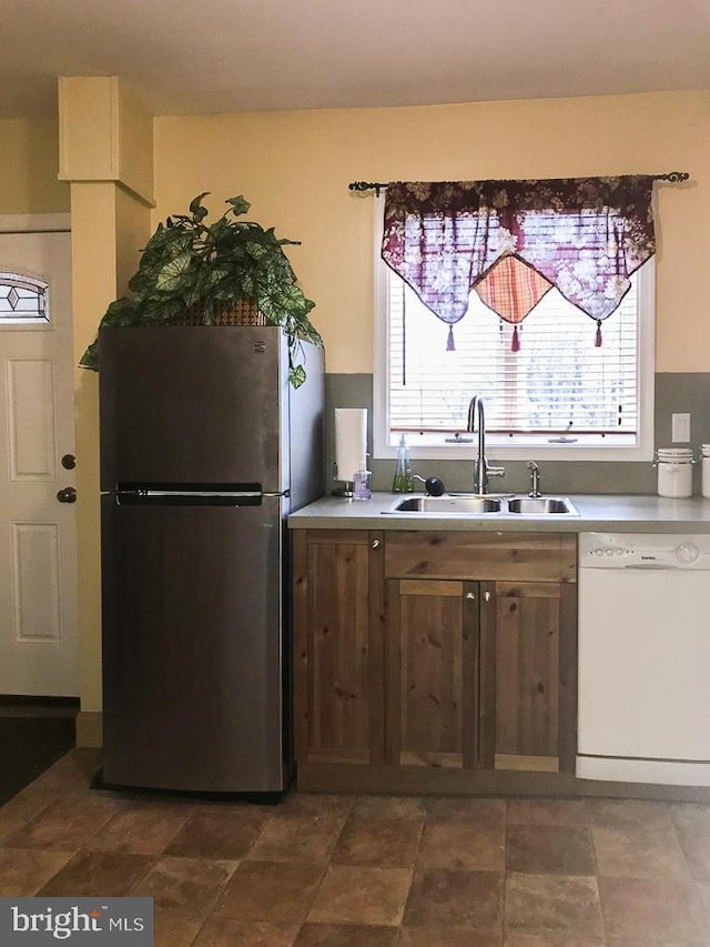 kitchen featuring white dishwasher, sink, and stainless steel fridge